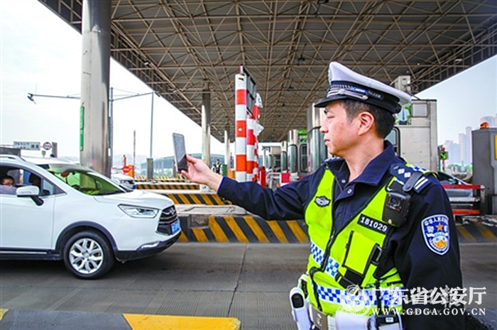 29日,广明高速罗格收费站便民服务点,交警正在使用警务app对通过